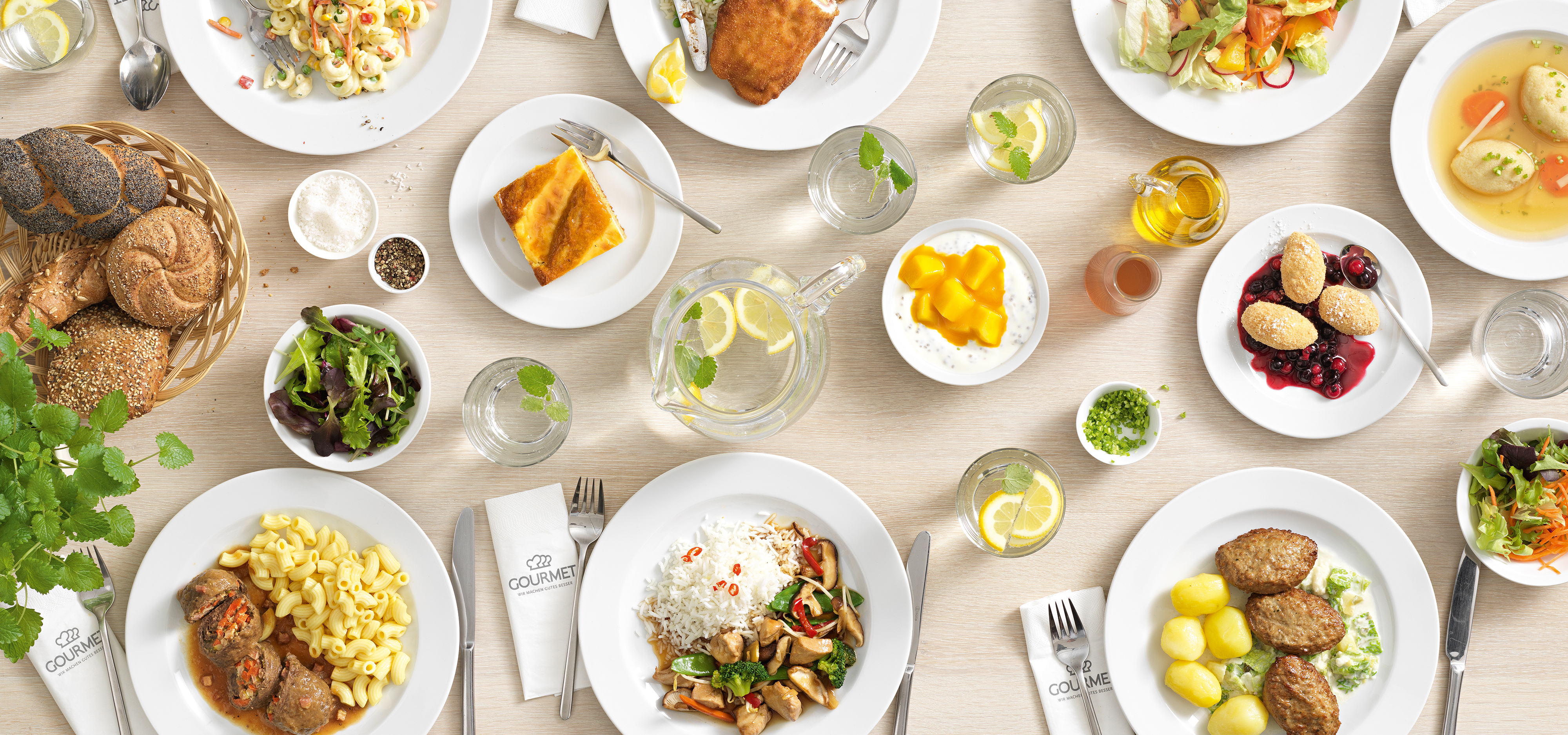 Ein Tisch, der mit vielen Tellern gefüllt ist, die eine bunte Auswahl an Speisen zeigen.