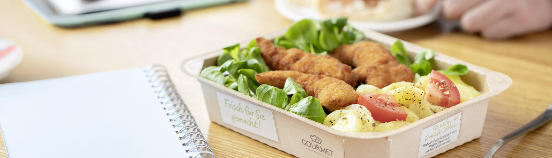Frischer Steirischer Backhendlsalat mit Kürbiskernöl in einer Papierschale